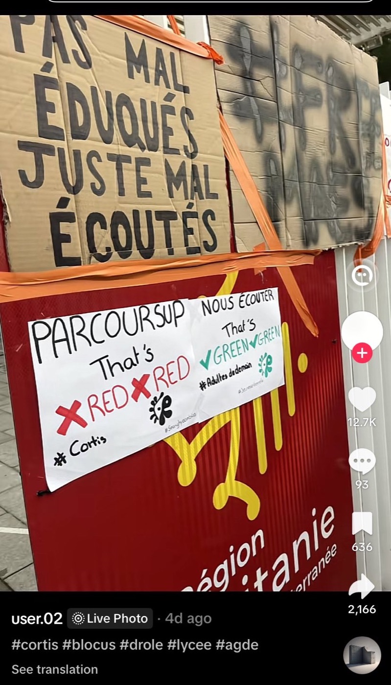 Protest signs taped to a fence at a French school reading Parcoursup that&rsquo;s RED RED, nous ecouter that&rsquo;s GREEN GREEN, with the hashtag Cortis, next to a cardboard sign reading pas mal eduques juste mal ecoutes