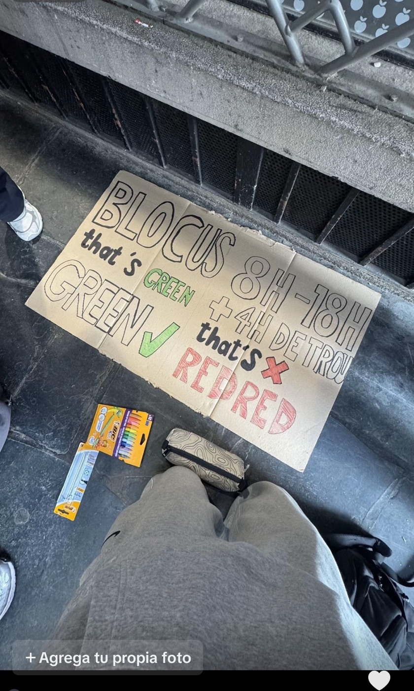 A cardboard protest sign on the floor of a French school reading BLOCUS that&rsquo;s GREEN GREEN and 8H-18H + 4H DE TROU that&rsquo;s RED RED, next to a pack of Bic pens