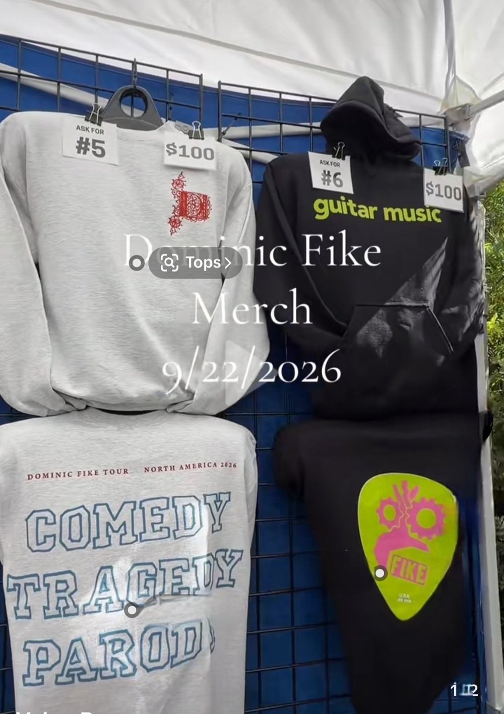 Dominic Fike tour merch stand showing the black guitar music hoodie as item number 6 at 100 dollars, next to the Comedy Tragedy Parody North America 2026 long sleeve