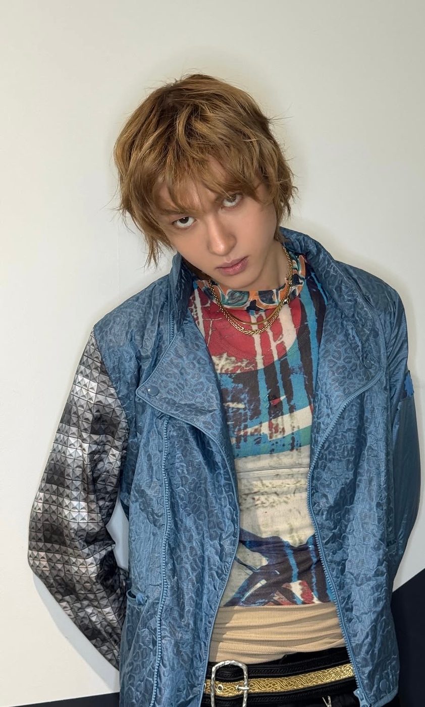 Martin of CORTIS in his Tokyo Inkigayo stage outfit: Jean Paul Gaultier printed mesh sleeveless top under a blue PUMA x MIHARA YASUHIRO nylon jacket