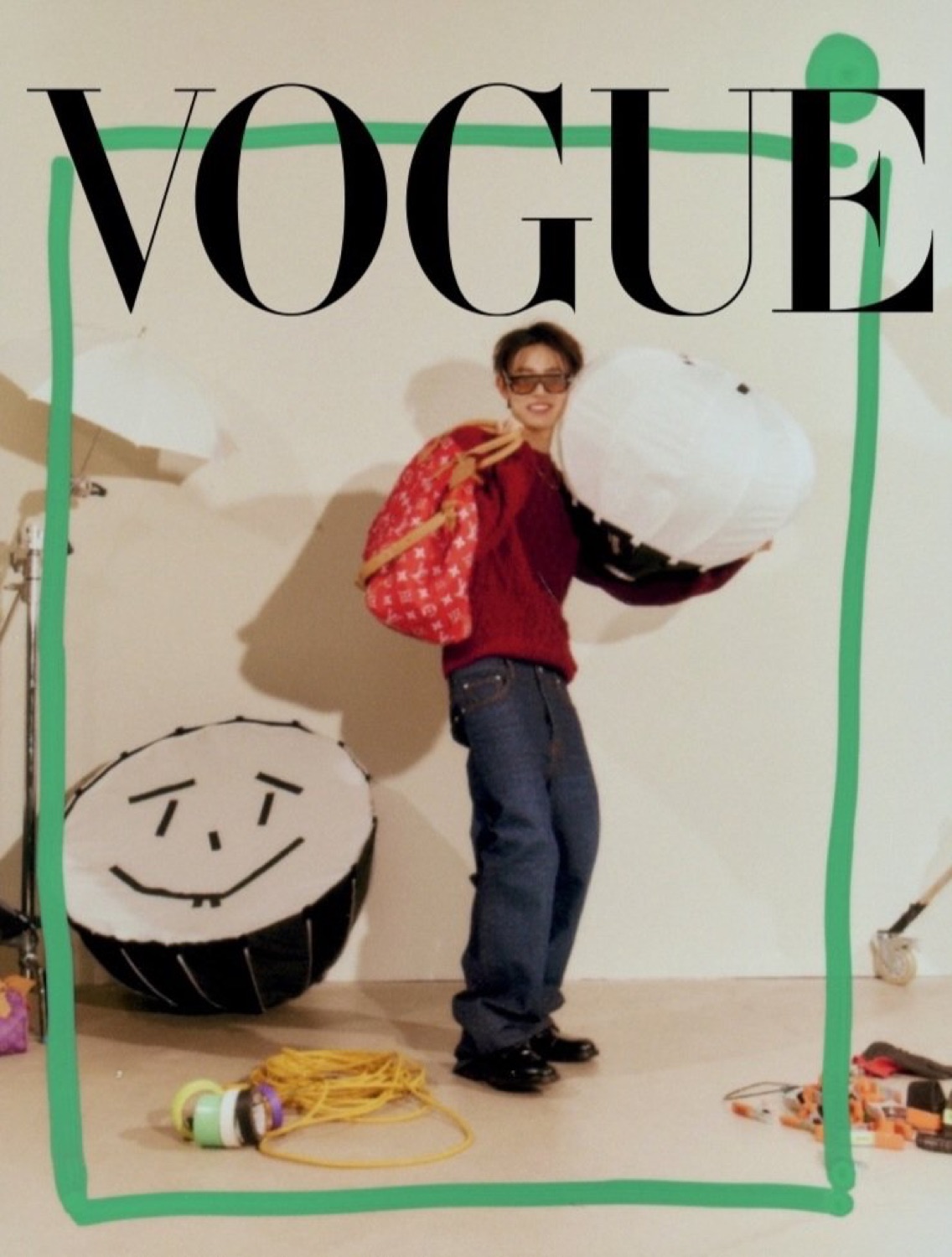 Seonghyeon of CORTIS in a red Louis Vuitton cable knit carrying studio umbrellas, inside a hand drawn green Vogue frame