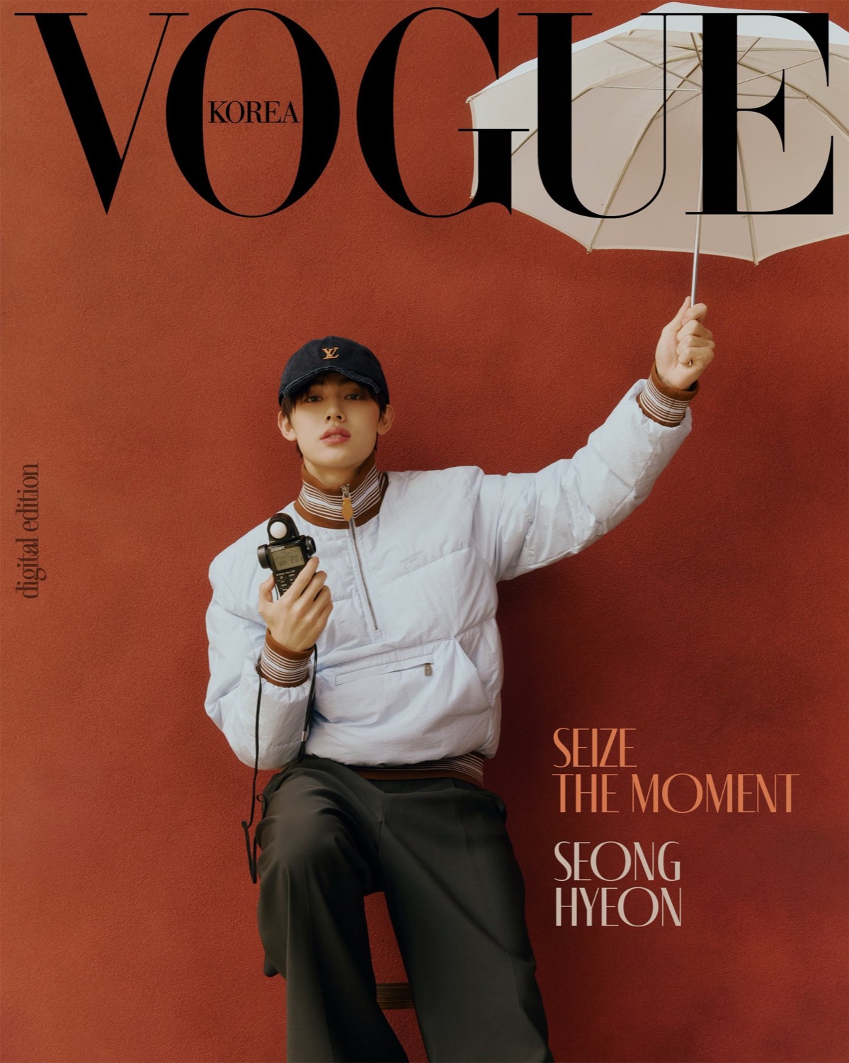 Seonghyeon of CORTIS on a second Vogue Korea digital cover, white puffer jacket and Louis Vuitton cap against a red backdrop, holding a light meter and a white umbrella