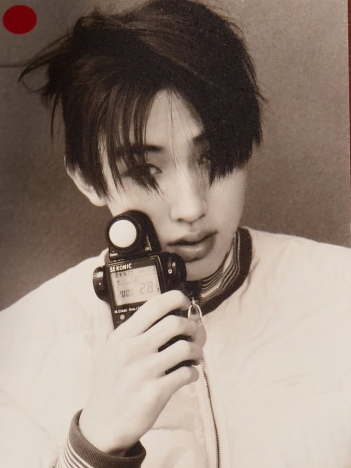 Sepia close up of Seonghyeon of CORTIS holding a Sekonic light meter up to his face