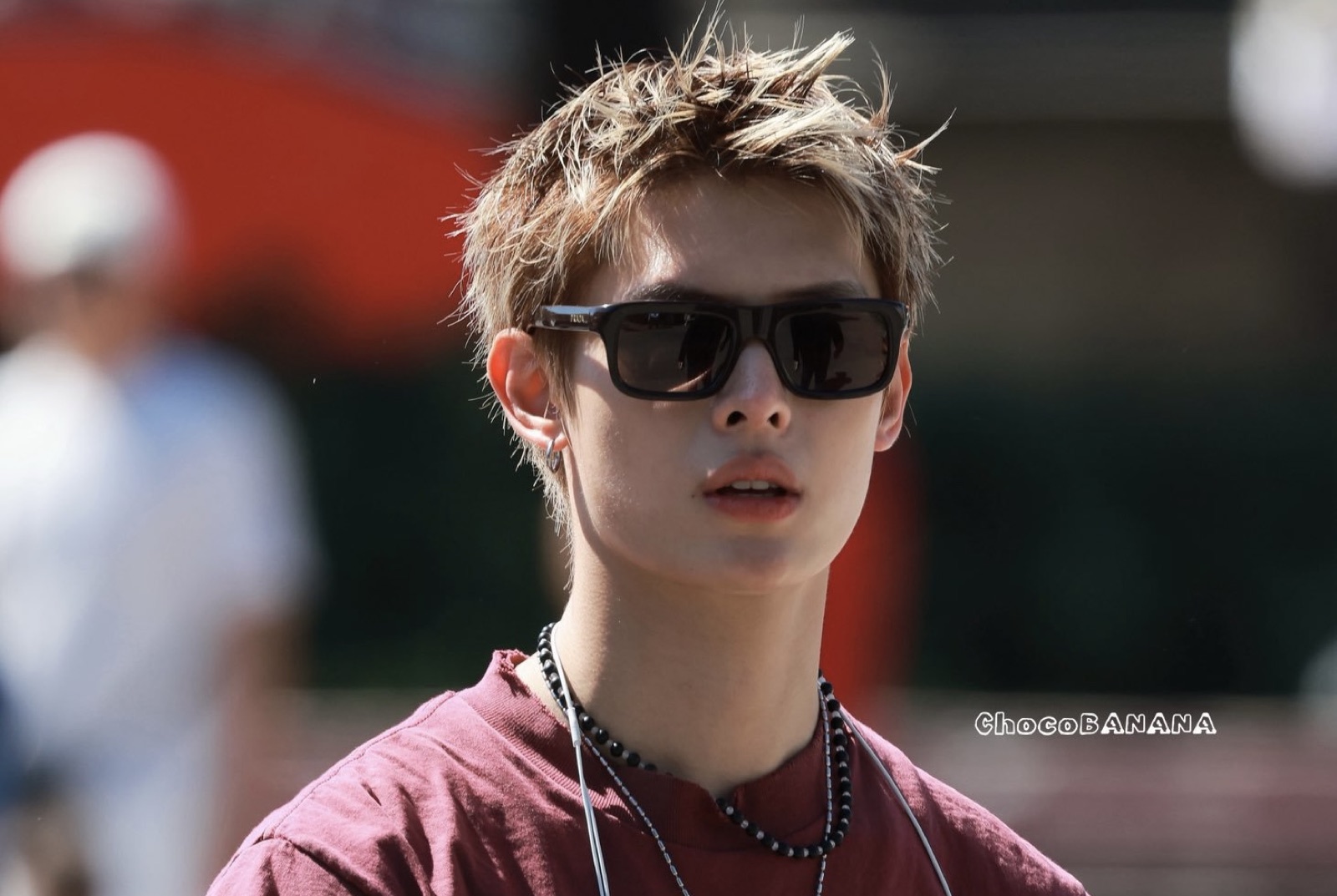 James of CORTIS in black sunglasses and a burgundy t-shirt