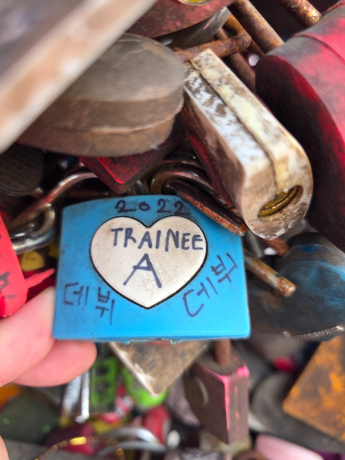 A blue padlock on a Korean lock wall reading 2022 Trainee A with the Korean words for debut and daebak