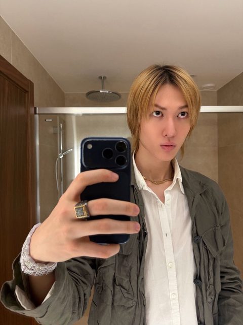 CORTIS Martin phone lock screen, blonde hair mirror selfie in a white shirt
